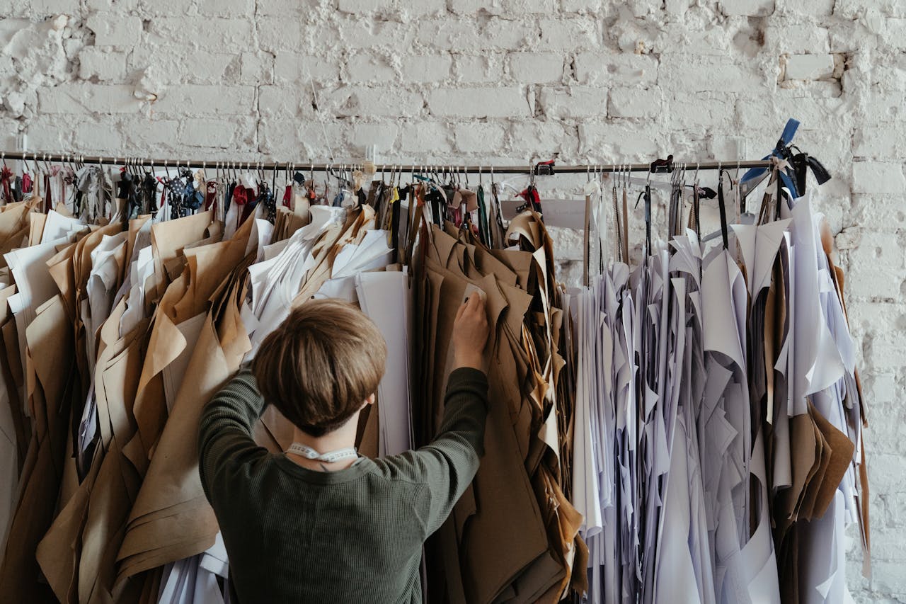 service-02 Back view of designer organizing sewing patterns against a rustic wall.
